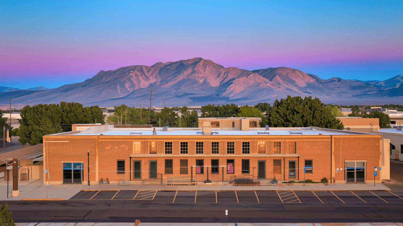 Aerial view of the historic Rail Yards Market building in Barelas, Albuquerque, with the Sandia Mountains visible in the background on a clear morning