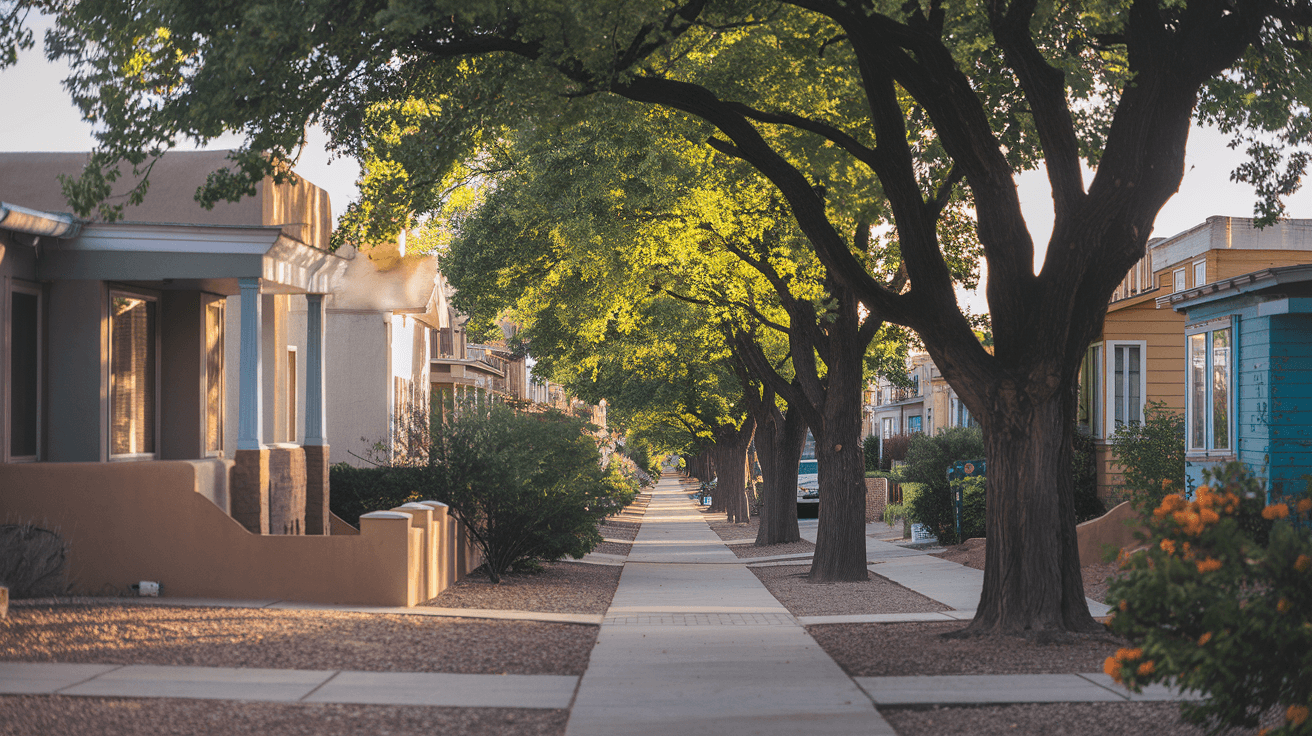 A tree-lined street in Nob Hill with adobe-style homes and mature cottonwood trees, late afternoon light casting long shadows across the sidewalk